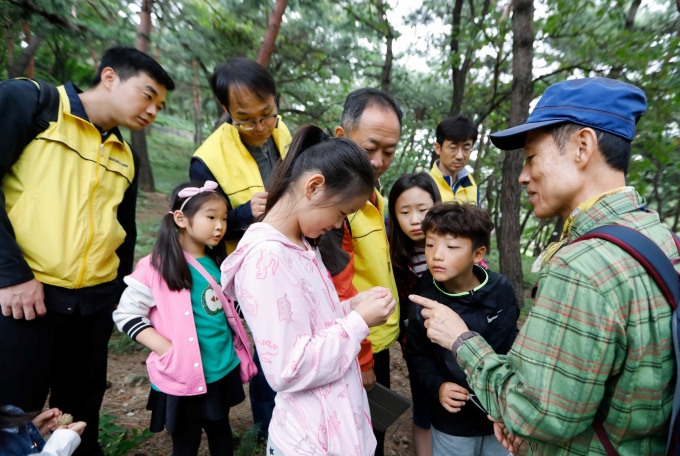 대림산업 임직원 가족들이 숲 해설가와 함께 남산 숲 체험 프로그램에 참여하고 있다. [사진=대림산업]