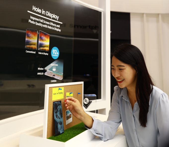 삼성디스플레이 직원이 'IMID 2019'에서 플렉시블 OLED로 구현한 홀디스플레이를 체험하고 있다. [출처=삼성디스플레이]