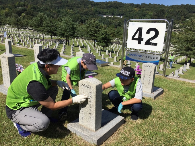 현대엔지니어링 임직원 가족봉사단이 국립서울현충원 42번 묘역을 방문해 묘역 관리 봉사활동을 펼치고 있다.  [사진=현대엔지니어링]