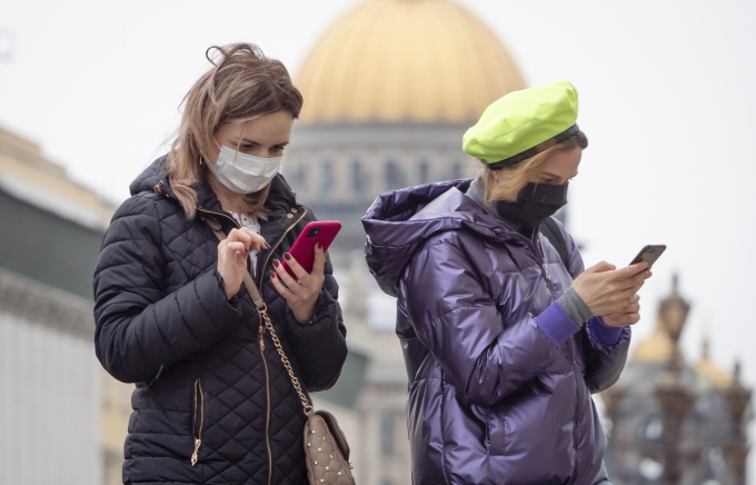 러시아 상트페테르부르크에서 코로나19 예방을 위해 마스크를 쓴 여성들이 스마트폰을 살펴보고 있다.  [상트페테르부르크=AP/뉴시스]]