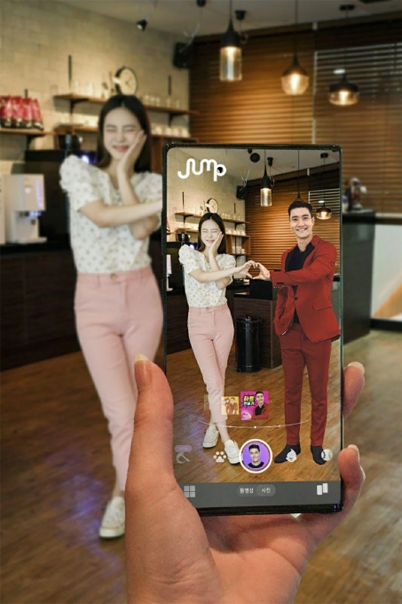 SK텔레콤 홍보모델이 점프 AR 앱에서 K팝 그룹 슈퍼주니어 멤버 최시원의 이미지를 소환해함께 셀카를 찍고 있다.  [출처=SKT]