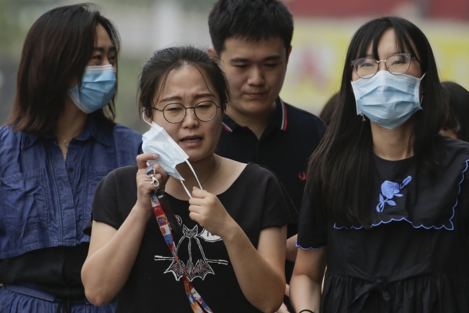 [베이징=AP/뉴시스] 중국 베이징에서 신종 코로나바이러스 감염증(코로나19) 예방을 위해 마스크를 쓴 동료들과 함께 걷던 한 여성이 답답한 듯 마스크를 벗고 있다. [뉴시스]