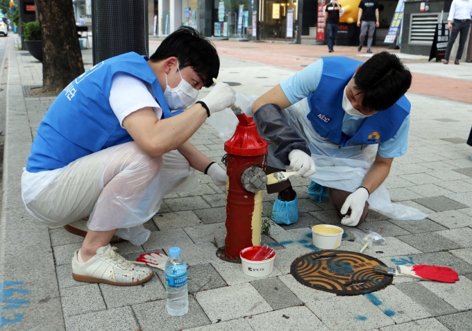 KCC 행복나눔 봉사단 직원들이 소화전에 색을 칠하고 있다. [KCC]