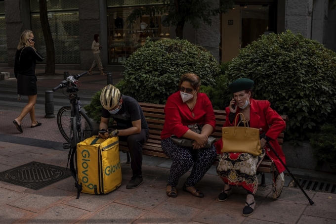 [AP/뉴시스] 마스크를 쓴 행인들이 스페인 마드리드의 공공 의자에 앉아 있다.