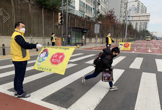 지난 26일 평택 동삭초등학교 앞에서 쌍용자동차 사내 사회공헌 프로그램 '네바퀴 동행' 로고가 새겨진 안전조끼를 입은 쌍용차 임직원들이 등굣길 학생들의 보행 지도를 하고 있다. [쌍용자동차]