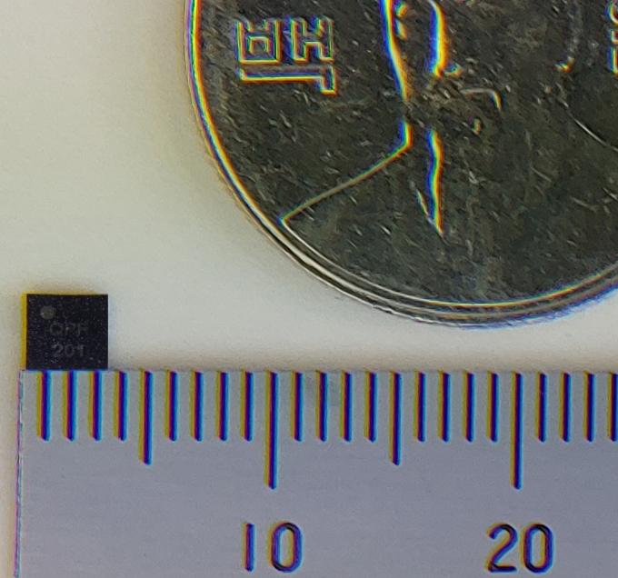 IoT 단말용 초소형 양자보안칩과 100원짜리 동전의 크기를 비교하는 모습. [출처=LG유플러스]