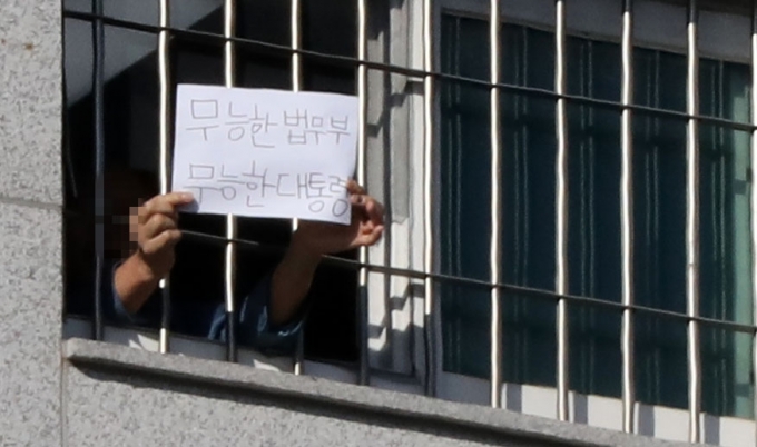 6일 서울 송파구 서울동부구치소에서 한 수용자가 종이에 '무능한 법무부 무능한 대통령'이라고 쓴 글을 취재진에게 보여주고 있다.  [뉴시스]