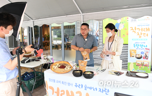 산림조합이 초복을 맞아 7일 오후 서울 송파구 산림조합중앙회 앞에서 임산물 소비 촉진행사 우리 숲에서 자란 직거래 장터-초복맞이 삼계탕 특판행사 라이브 쇼핑 행사를 개최했다. 쇼호스트로 나선 개그맨 송영길과 표순영 산림조합중앙회 임산물유통센터 비욘드팜 점장이 제품을 소개하고 있다.