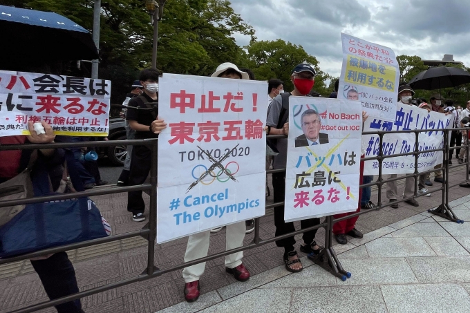 지난 16일 일본 히로시마에 있는 히로시마 원폭 위령비 앞에서 도쿄 올림픽 반대 시위대가 "바흐, 히로시마에 오지 마"라는 현수막 등을 들고 토마스 바흐 국제올림픽위원회(IOC) 위원장의 방문에 반대하고 있다. [사진=뉴시스]