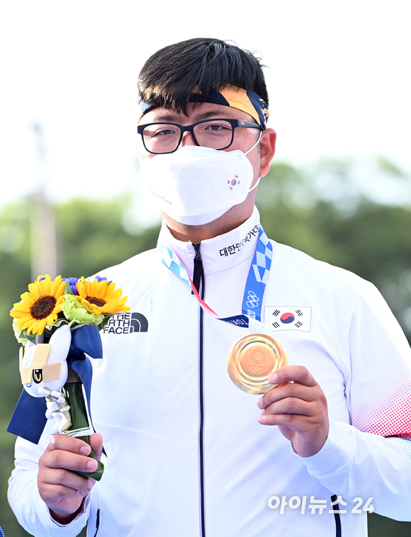 양궁 국가대표 김우진이 26일 오후 일본 도쿄 유메노시마 공원 양궁장에서 열린 2020 도쿄올림픽 남자양궁 단체전 대만과의 결승전에서 금메달을 따낸 후 기념 촬영을 하고 있다.