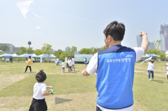 동양생명 관계자가 '소아암 완치 기원 연날리기' 행사에 참여한 어린이와 함께 연을 날리고 있다. [사진=동양생명]