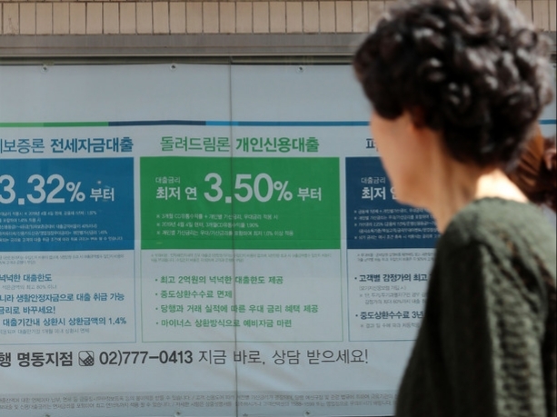 한 시민이 벽에 걸린 대출 광고를 보고 있다. [사진=뉴시스]