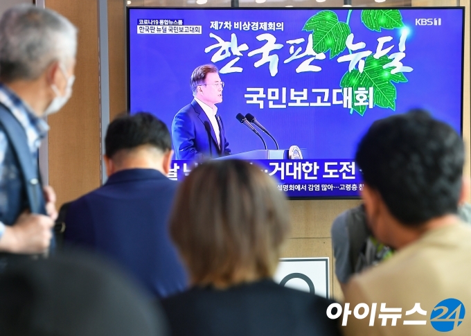 14일 오후 서울 용산구 서울역에서 시민들이 문재인 대통령의 '한국판 뉴딜 국민보고대회'를 시청하고 있다.