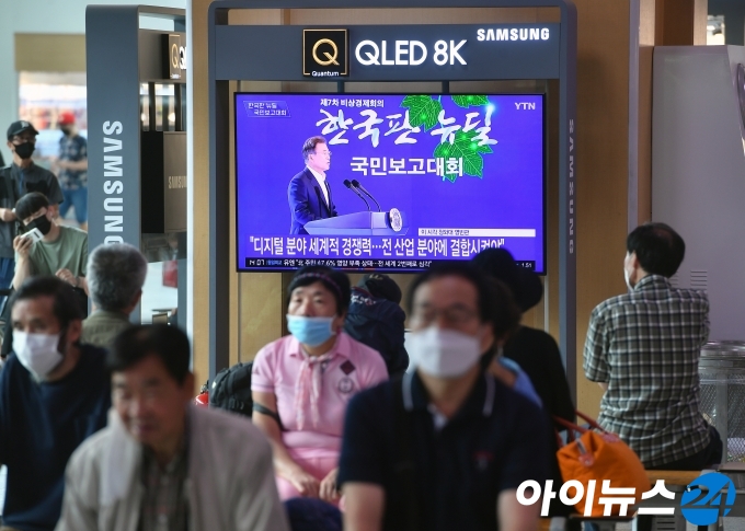 14일 오후 서울 용산구 서울역에서 시민들이 문재인 대통령의 '한국판 뉴딜 국민보고대회'를 시청하고 있다.