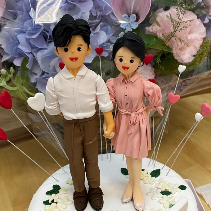  조유리가 자신의 인스타그램에 올린 부부인형. 부부가 케이크 위에서 다정하게 손을 잡고 있다.[사진 = 조유리 인스타그램 ]