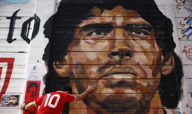 아르헨티나 출신 축구 레던드 마라도나의 사망 소식이 전해진 26일(한국시간) 수도 부에노스아리에스에 있는 벽화 앞에서 한 팬이 추도를 하고 있다. [사진=뉴시스]