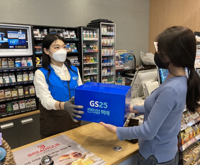 한 고객이 GS25에서 점원에게 접수한 반값택배를 건네고 있다. [사진=GS25]